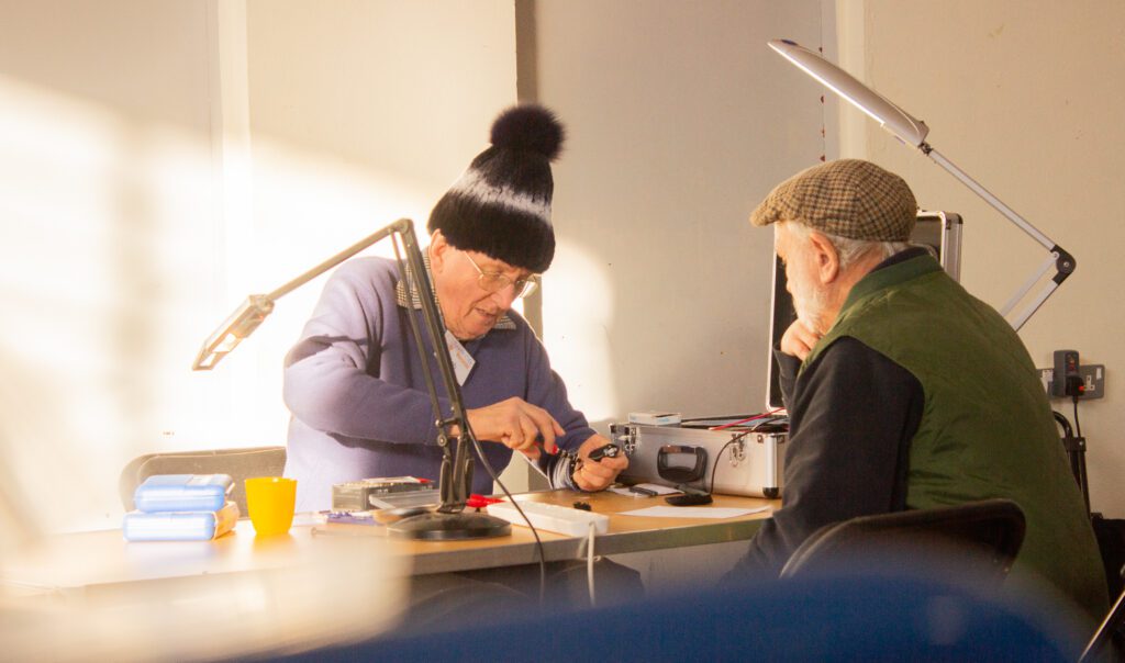 Two people sat looking at items on a table.