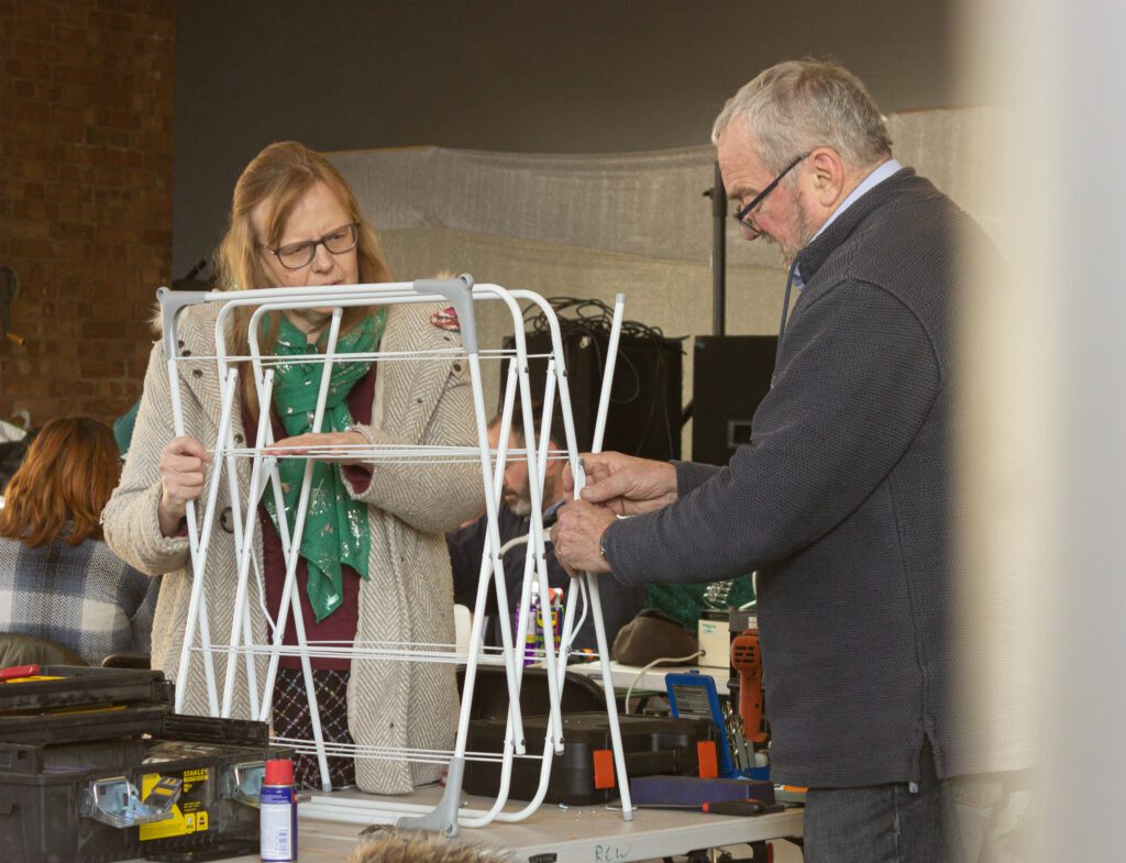 Two people stood holding a clothes dryer.