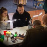 Four people sat looking at things at a table.