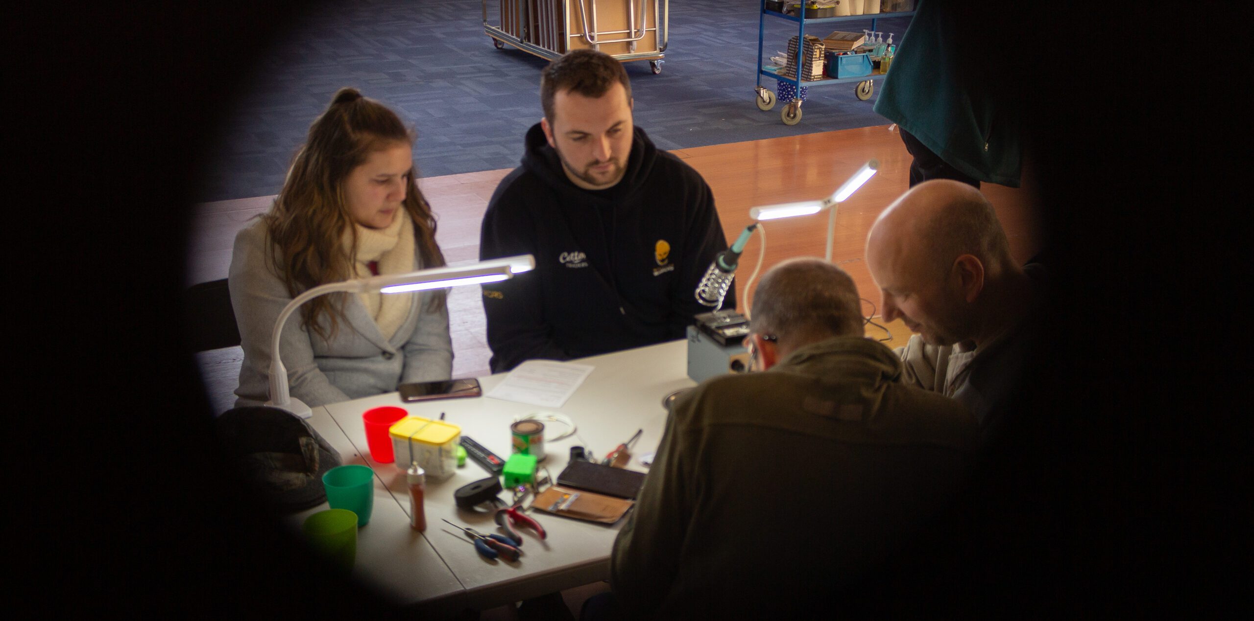 Four people sat looking at things at a table.