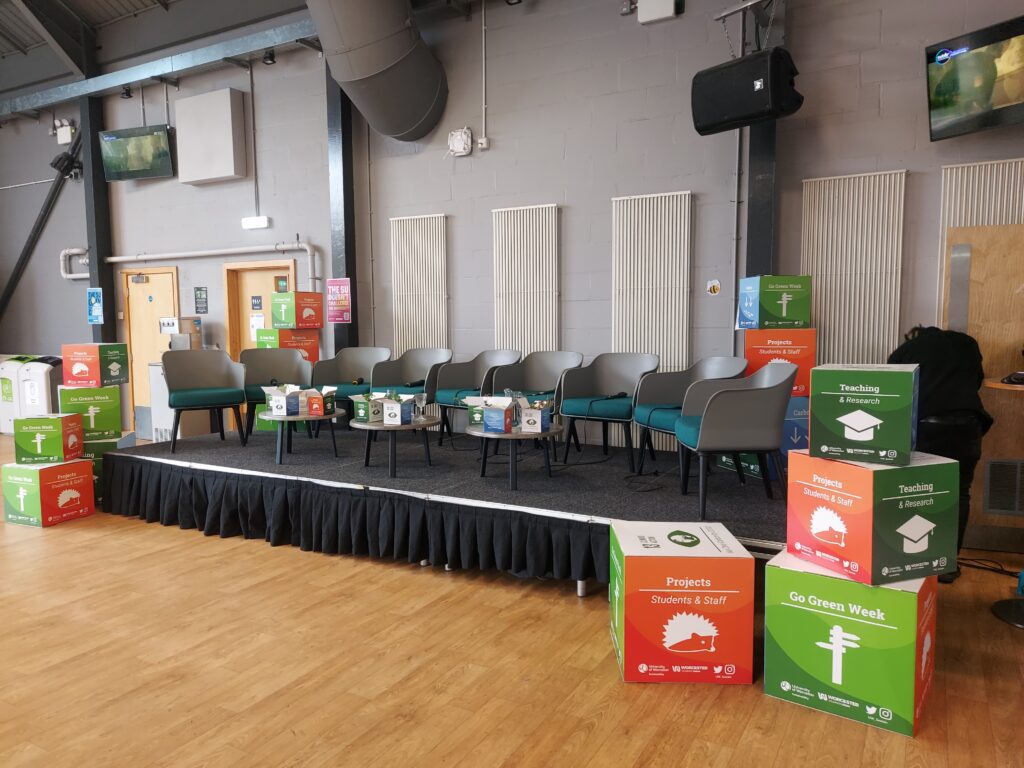 A stage with a row of chairs and colourful boxes on the side at Go Green Week.
