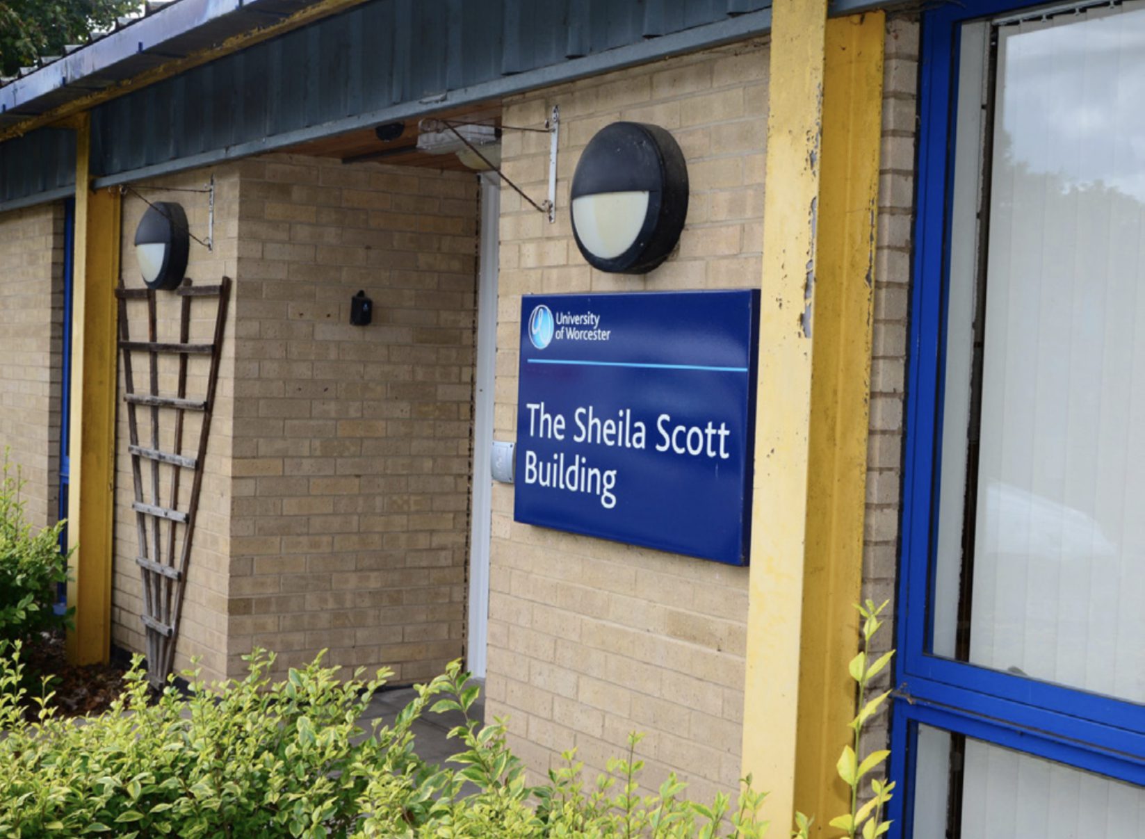 Image of the front entrance to the Sheila Scott building with a building sign on the wall